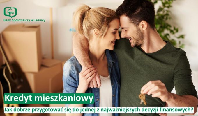 Uśmiechnięta młoda para tuląca się do siebie na tle kartonowych pudeł przeprowadzkowych. Mężczyzna trzyma w dłoni klucze do nowego mieszkania. W lewym górnym rogu logotyp Banku Spółdzielczego w Leśnicy. Na dole napis: „Kredyt mieszkaniowy. Jak dobrze przygotować się do jednej z najważniejszych decyzji finansowych?”