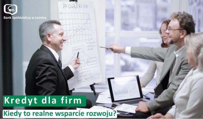 Trzy osoby siedzące przy drewnianym stole – doradczyni bankowa w czarnym żakiecie oraz para klientów. Na stole leżą dokumenty i otwarty laptop, a doradczyni wskazuje coś na ekranie smartfona. W lewym górnym rogu logotyp Banku Spółdzielczego w Leśnicy. Na dole napis: „Oszczędności. Dlaczego warto mieć finansową poduszkę bezpieczeństwa?”